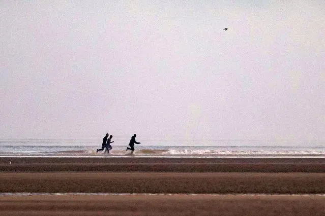 Smugglers run away after migrants board a boat on the beach of Gravelines, near Dunkirk, northern France on October 12, 2022. (Photo by Sameer Al-Doumy/AFP Photo)