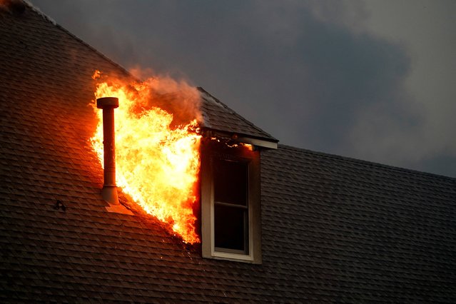Fire burns on the roof of a building during a wildfire outbreak in Stillwater, Oklahoma, on March 14, 2025. (Photo by Nick Oxford/Reuters)