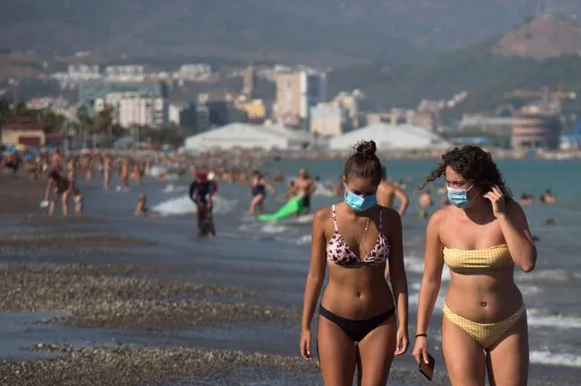 Women wearing face masks walk along La Misericordia Beach in Malaga on July 22, 2020. The world's second-most popular destination after France, Spain was badly hit by the coronavirus that has claimed more than 28,400 lives and dealt a major blow to its tourism industry, which accounts for 12 percent of GDP. (Photo by Jorge Guerrero/AFP Photo)
