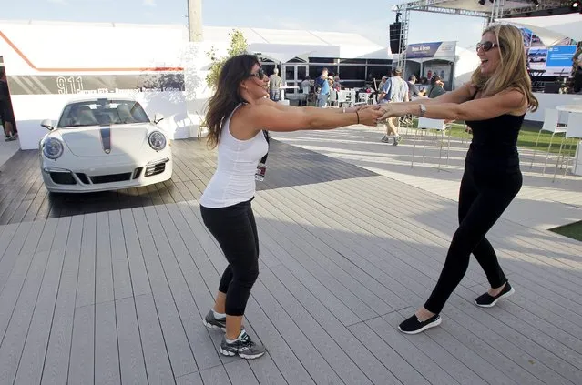 Jennifer Elbe (L) and Kay Payer dance to live music during the Porsche Rennsport Reunion V at Laguna Seca Raceway near Salinas, California, September 26, 2015. The three-day reunion is billed by organizers as the world's largest gathering of Porsche racecars, renowned drivers, and Porsche collector cars. (Photo by Michael Fiala/Reuters)