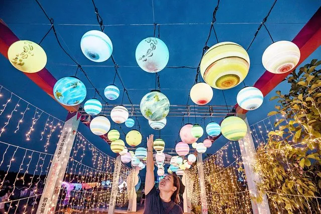 A person touches a colorful light ball at the opening ceremoby of the first Windmill and Light Show Festival in Xingan county, Ji'an city, east China's Jiangxi province, 25 July 2020. (Photo by Imaginechina via AP Images)