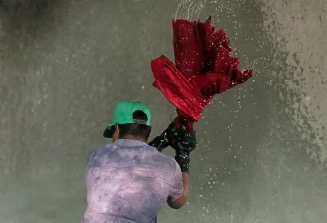 A man washes shirts in a water tank at a laundry, amid concerns about the spread of the coronavirus disease (COVID-19), in Colombo, Sri Lanka, July 22, 2020. (Photo by Dinuka Liyanawatte/Reuters)