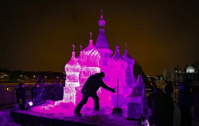 A man cleans snow in front of an ice sculpture during the festival “Snow and Ice in Moscow” in the park Muzeon in Moscow, 28 December 2022. The ice and snow sculptures up to 7 meters high installed in the park. The main theme of festival is the wonders and heritage of Russia. The festival will run from 28 December 2022 to 28 January 2023. (Photo by Yuri Kochetkov/EPA/EFE)