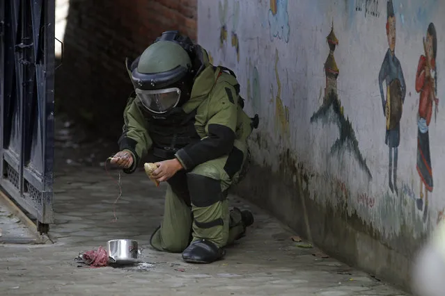 A Nepalese bomb squad member inspects a pressure cooker bomb after detonating it at the school in Kathmandu, Nepal, Tuesday, September 20, 2016. Police in Nepal say small bombs have exploded outside two schools in the capital, but no injuries and only minor damage were reported. Unexploded bombs were found at five other schools in the city. (Photo by Niranjan Shrestha/AP Photo)