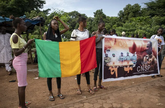 People hold a banner showing Col. Assimi Goita, leader of the junta which is now running Mali and calls itself the National Committee for the Salvation of the People, outside a conference in Bamako, Mali, Thursday, September 10, 2020. Leaders of Mali's military junta who deposed the West African country's president last month are meeting with political parties and civil society groups to outline a transition to a civilian government and, ultimately, elections. (Photo by AP Photo/Stringer)