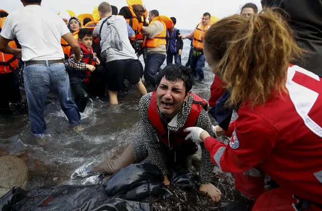 A Greek Red Cross volunteer comforts a crying Syrian refugee moments after disembarking from a flooded raft at a beach on the Greek island of Lesbos after crossing a part of the Aegean Sea from the Turkish coast on an overcrowded raft October 20, 2015. (Photo by Yannis Behrakis/Reuters)