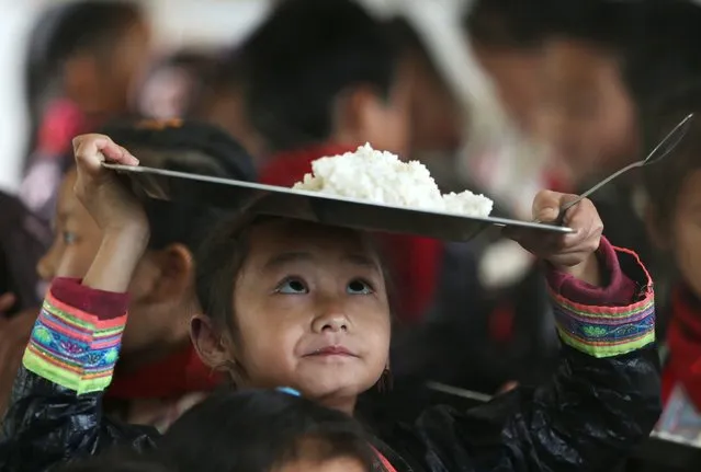 An ethnic Miao minority child wearing traditional costume carries a plate of rice during lunchtime at the village of Basha in Congjiang county, Guizhou province, November 27, 2014. The village, an ethnic Miao settlement with a population of 2,200, is believed to be the last community authorized by the Chinese government to keep guns. (Photo by Sheng Li/Reuters)