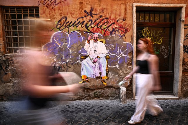 People walk near an artwork depicting Pope Francis, following the death of the pontiff, in Rome, Italy, on April 22, 2025. (Photo by Dylan Martinez/Reuters)