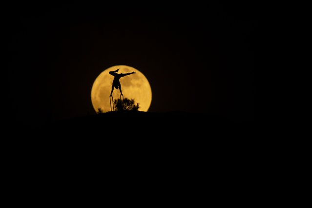 Full moon is seen behind a silhouette of a man doing gymnastics in Erbil, Iraq on May 12, 2025. (Photo by Ahsan Mohammed Ahmed Ahmed/Anadolu via Getty Images)