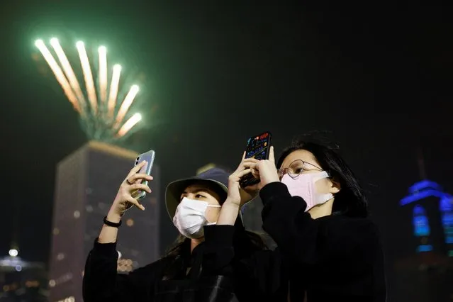 People wear masks as they take photos of fireworks during an event to celebrate New Year in Hong Kong, China, January 1, 2022. (Photo by Tyrone Siu/Reuters)
