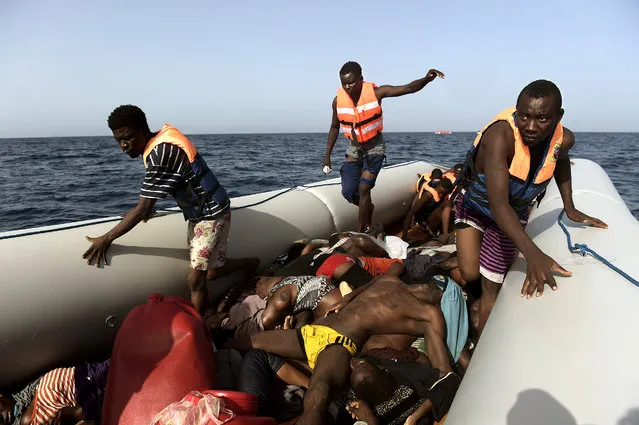 Migrants step over dead bodies while being rescued by members of Proactiva Open Arms NGO in the Mediterranean Sea, some 12 nautical miles north of Libya, on October 4, 2016. At least 1,800 migrants were rescued off the Libyan coast, the Italian coastguard announced, adding that similar operations were underway around 15 other overloaded vessels. (Photo by Aris Messinis/AFP Photo)
