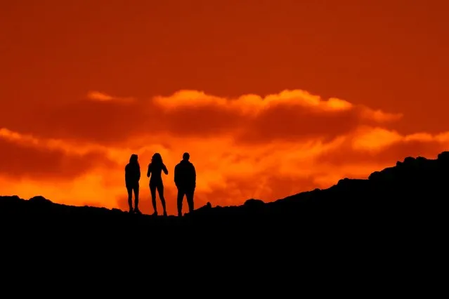 Hikers are silhouetted against the sky as they view the sunset from a ridge at Papago Park, Thursday, March 2, 2023, in Phoenix. (Photo by Charlie Riedel/AP Photo)