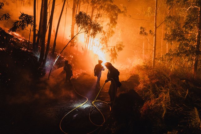 Members of the XVII and XVIII Galician forest firefighting brigades work through the night to control a wildfire in Oia, Pontevedra, Galicia, Spain on August 22, 2025. Crews are seen creating firebreaks, extinguishing flames with water, and using bulldozers to combat the blaze. (Photo by Pedro Pascual/Anadolu via Getty Images)