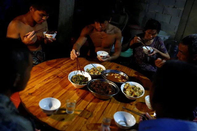 Worker Shi Shenwei (2nd L) and his colleagues and family members eat dinner in the yard of an old farm house in the village of Huangshan, near Quanzhou, Fujian Province, China, September 28, 2016. (Photo by Thomas Peter/Reuters)