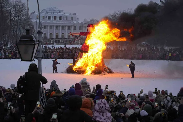 People watch as an effigy of Lady Winter burns during Maslenitsa (Shrovetide) holiday celebrations in St. Petersburg, Russia, Sunday, February 26, 2023. (Photo by Dmitri Lovetsky/AP Photo)