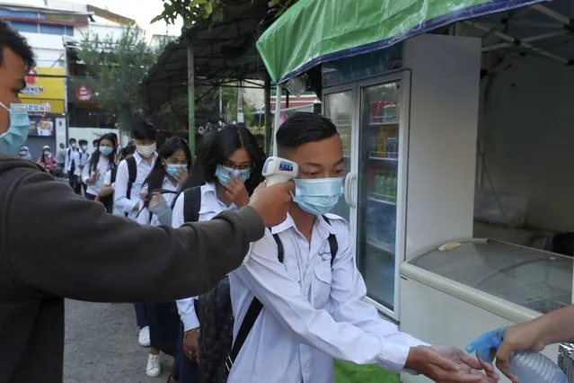 Students have their temperature checked and disinfect their hands to avoid the contact of coronavirus before their morning classes at Preah Sisowath high school, in Phnom Penh, Cambodia, Monday, November 23, 2020. Cambodia on Monday reopened schools after the country banned all state-organized events in the capital and a neighboring province for two weeks to prevent the spread of the coronavirus after a number of people connected to a Hungarian official's visit tested positive in early the month of November. (Photo by Heng Sinith/AP Photo)