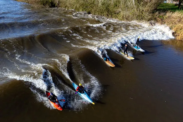Surfers and kayakers ride a “four-star” Severn Bore at Minsterworth, Gloucestershire, United Kingdom on Wednesday, March 22, 2023. The bore, a large surge wave, is formed in the estuary of the River Severn, where the tidal range is the second highest in the world, and is caused when the incoming tide is funneled into an increasingly narrow channel against the current of the river. (Photo by Ben Birchall/PA Images via Getty Images)