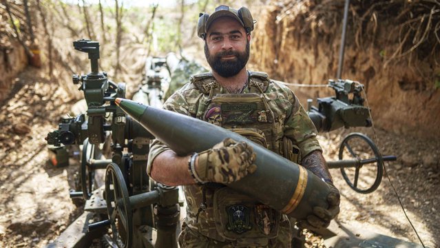 Ukrainian serviceman, aka Bronson, of the 148th artillery brigade carry a 155mm shell in front of M777 howitzer at the frontline in Zaporizhzhia region, Ukraine, on Thursday, August 7, 2025. (Photo by Evgeniy Maloletka/AP Photo)