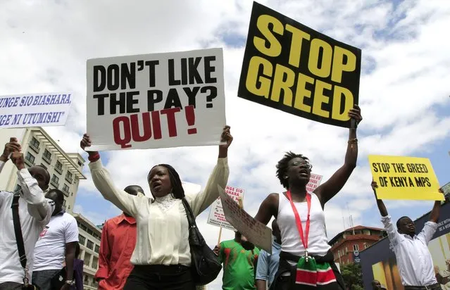 Protestors carry placards as they participate in a demonstration against lawmakers' salary demands near parliament buildings in the capital Nairobi, May 14, 2013. (Photo by Thomas Mukoya/Reuters)