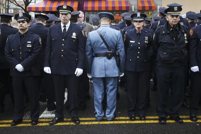 Law enforcement officers stand, with some turning their backs, as New York City Mayor Bill de Blasio speaks on a monitor outside the funeral for NYPD officer Wenjian Liu in the Brooklyn borough of New York January 4, 2015. Tens of thousands of law enforcement officers from across the country gathered on Sunday for the funeral of the second of two New York City policemen killed last month in an ambush that galvanized critics of Mayor de Blasio. (Photo by Shannon Stapleton/Reuters)