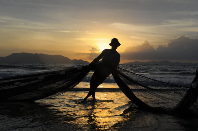 In this picture taken on September 26, 2016 show a fisherman cleaning a net in Banda Aceh, Aceh province, after overnight fishing. Indonesia's economy accelerated in the second quarter as government stimulus plans came to fruition, a report said last week. (Photo by Chaideer Mahyuddin/AFP Photo)