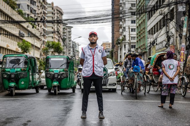 Commuters wait at a road crossing while Bangladeshi students control the traffic as police went on strike in Dhaka on August 9, 2024. Nobel laureate Muhammad Yunus led a solemn tribute to Bangladesh's fallen independence heroes on August 9 in the first act of his interim government, after a student-led uprising forced predecessor Sheikh Hasina into exile. Yunus, 84, was sworn in on Thursday night after returning home from Europe at the request of protest leaders, following the sudden end of Hasina's 15-year rule. (Photo by Luis Tato/AFP Photo)