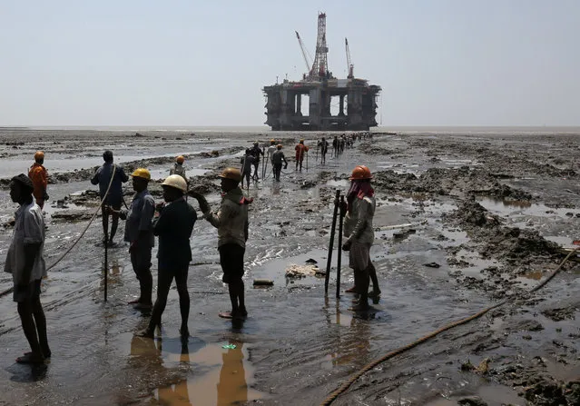 Workers prepare to tie a rope to a decommissioned oil rig to dismantle it at the Alang shipyard in Gujarat, India, May 29, 2018. (Photo by Amit Dave/Reuters)