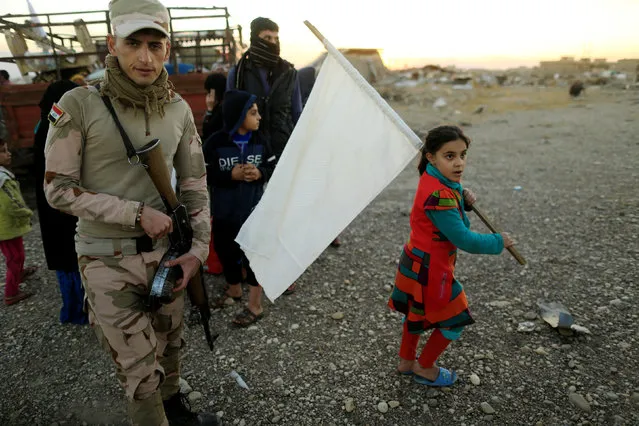 A girl who had just fled Kokjali near Mosul carries a white flag as she arrives with her family at a Peshmerga checkpoint east of Mosul, Iraq November 3, 2016. After finding the road to the camp for displaced people closed, the family prepared to spend a night in an open field near the checkpoint. (Photo by Zohra Bensemra/Reuters)