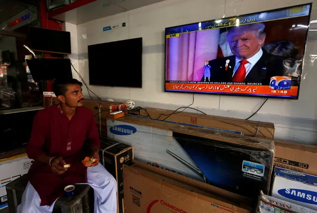 A salesman eats breakfast as he looks at a television a screen displaying Donald Trump's victory speech, after winning the U.S. presidential election, in Karachi, Pakistan, November 9, 2016. (Photo by Akhtar Soomro/Reuters)