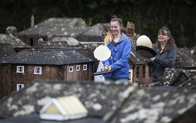 Mother and daughter volunteers Niki, right, and Rachel practice their pancake tossing technique in the streets of Wimborne model town and gardens before taking part in the Wimborne Minster virtual pancake race, in Wimborne, England, Tuesday February 16, 2021.  Although a physical race cannot take place this year due to the coronavirus restrictions, Wimborne Minster has invited people to film themselves tossing a pancake for 30 seconds and posting it to Facebook. (Photo by Andrew Matthews/PA Wire via AP Photo)