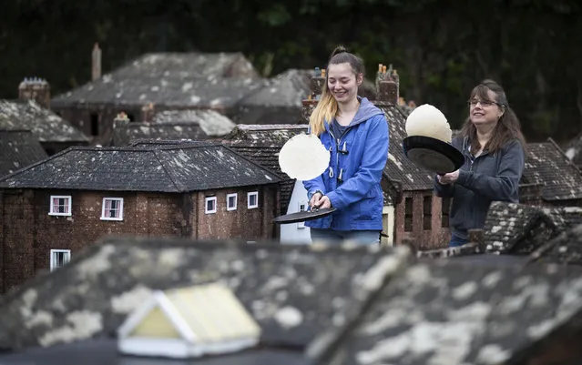 Mother and daughter volunteers Niki, right, and Rachel practice their pancake tossing technique in the streets of Wimborne model town and gardens before taking part in the Wimborne Minster virtual pancake race, in Wimborne, England, Tuesday February 16, 2021. Although a physical race cannot take place this year due to the coronavirus restrictions, Wimborne Minster has invited people to film themselves tossing a pancake for 30 seconds and posting it to Facebook. (Photo by Andrew Matthews/PA Wire via AP Photo)