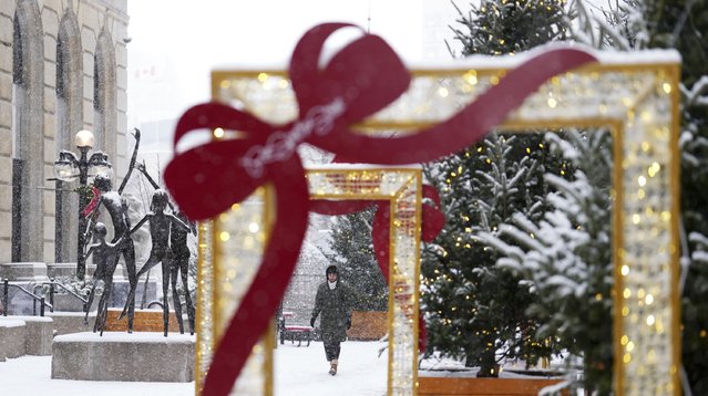 A pedestrian walks through the falling snow in downtown Ottawa, December 4, 2024. (Photo by Sean Kilpatrick/The Canadian Press via AP Photo)