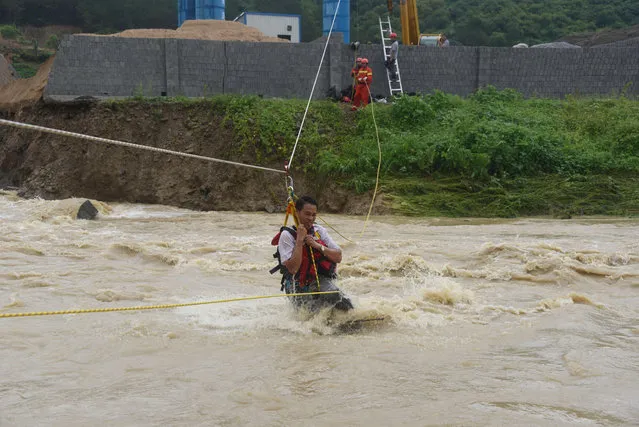 This photo taken on June 24, 2018 shows Chinese rescuers helping residents to evacuate in Tianlin county in China's southern Guangxi region. Floods and landslides caused by sustained rains have killed three people and affected more than 90,000 people in Guangxi. (Photo by AFP Photo/Stringer)