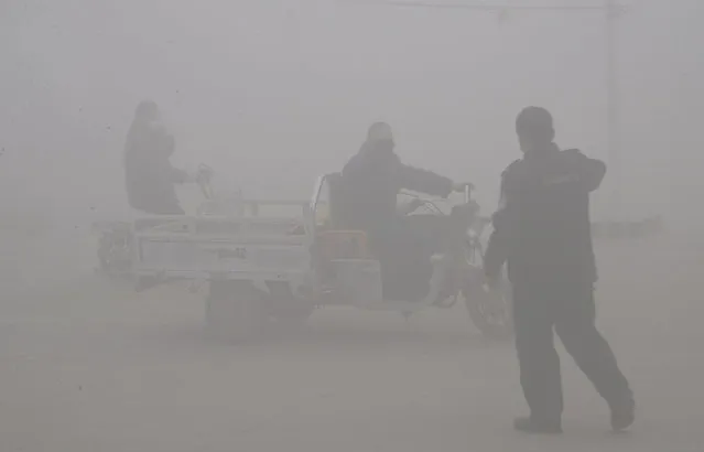 A policeman talks to the driver of a motor-tricycle on a road amid heavy haze in Handan city in northern China's Hebei province Thursday, December 24, 2015. Meteorological authorities in Hebei, a province which neighbors Beijing and is regarded as China's most polluted, issued its first red alert for smog on Tuesday as more Chinese cities are issuing their first red alerts for pollution in response to forecasts of heavy smog. (Photo by Chinatopix via AP Photo)