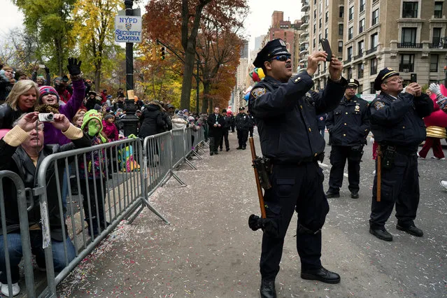 New York City police officers join spectators taking pictures as a float carrying Santa Claus passes by during the Macy's Thanksgiving Day Parade in New York Thursday, November 24, 2016. (Photo by Craig Ruttle/AP Photo)