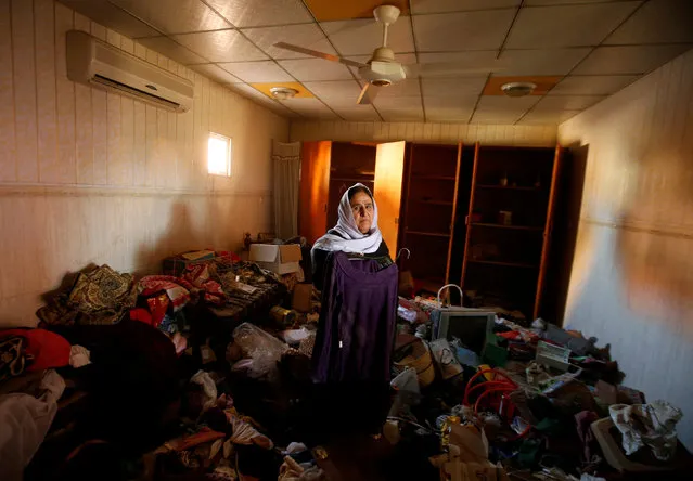 An Iraqi Kurdish woman looks on while inspecting her belongings inside her damaged house after returning to it in the town of Bashiqa which was retaken by Kurdish Peshmerga fighters following a battle with Islamic State militants, north of Mosul, Iraq November 29, 2016. (Photo by Mohammed Salem/Reuters)