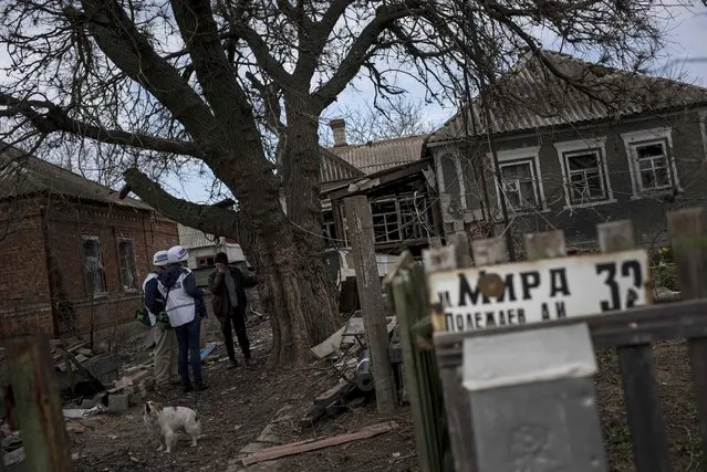 OSCE observers speak with a local woman while patrolling in the village of Shyrokyne, eastern Ukraine, Thursday, April 16, 2015. The sign in front reads Mir (Peace) Street. Shyrokyne, a village on the Azov Sea that has been the epicenter of recent fighting, has changed hands repeatedly throughout the conflict.  (AP Photo/Evgeniy Maloletka)