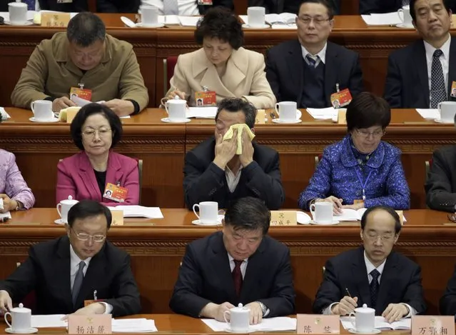 A delegate wipes his face during the opening session of the Chinese People's Political Consultative Conference (CPPCC) at the Great Hall of the People in Beijing, March 3, 2015. REUTERS/Jason Lee