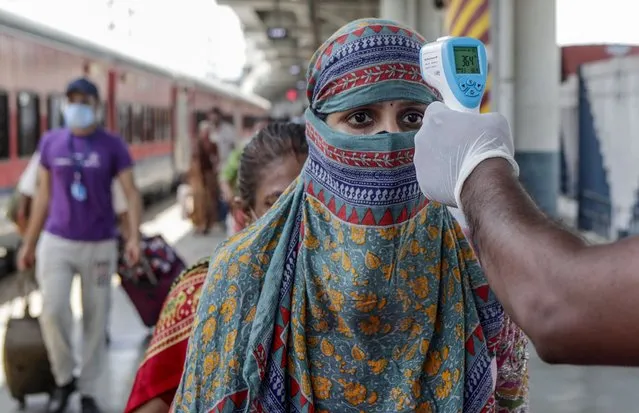A health worker screening travelers to test for COVID-19 at train station in Mumbai, India, Monday, May 24,2020. (Photo by Rajanish Kakade/AP Photo)