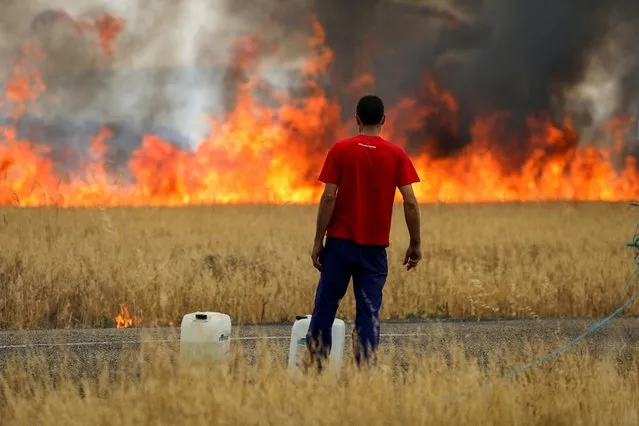 A shepherd watches a fire burning a wheat field between Tabara and Losacio, during the second heatwave of the year, in the province of Zamora, Spain on July 18, 2022. (Photo by Isabel Infantes/Reuters)