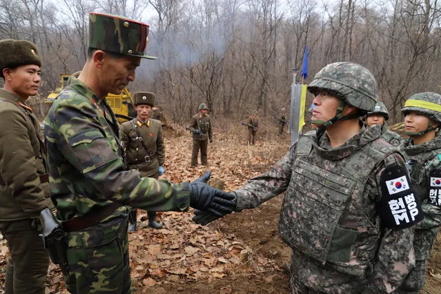 A South Korean military officer (R) and a North Korean military officer shake hands during an operation to reconnect a road across the Military Demarcation Line inside the Demilitarised Zone (DMZ) separating the two Koreas November 22, 2018. (Photo by The Defense Ministry/Yonhap via Reuters)