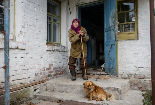 Yevdokiia Beznoshchenko, 78, stands near her house in a Chornobyl exclusion zone village from which the locals were evacuated in 1986 around the Chornobyl nuclear power plant near a Belarus border, amid Russia's attack on Ukraine, in Ukraine on October 18, 2023. This overgrown wilderness virtually devoid of people where buildings disappeared under a tangle of foliage is still home to a handful of pensioners who have stubbornly resisted leaving and vitally depend on Ukraine's military aid since the bridges were destroyed due to Russia's attack on Ukraine. (Photo by Gleb Garanich/Reuters)