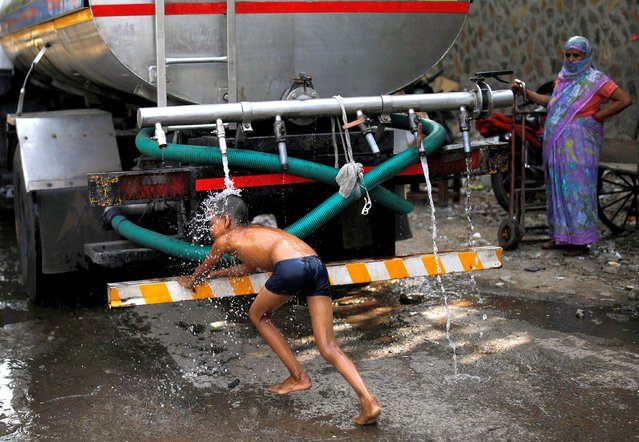 A boy bathes under a tap of a municipal tanker on a hot summer day in New Delhi, India, July 6, 2021. (Photo by Adnan Abidi/Reuters)
