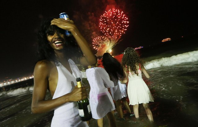 Revelers celebrate during fireworks marking the start of the New Year on Copacabana beach on January 1, 2017 in Rio de Janeiro, Brazil. Brazilian revelers traditionally dress in white to honor the New Year's holiday along with the Brazilian Goddess of the Sea- Iemanja. (Photo by Mario Tama/Getty Images)
