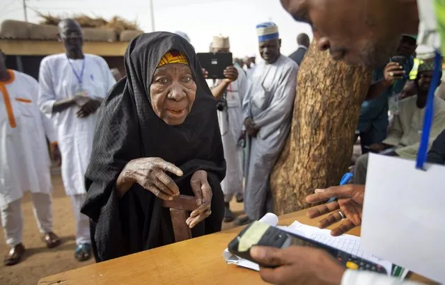 An elderly Nigerian woman arrives to validate her voting card using a fingerprint reader, prior to casting her vote later in the day, in the home town of opposition candidate Gen. Muhammadu Buhari, in Daura, Nigeria Saturday, March 28, 2015. Nigerians went to the polls Saturday in presidential elections which analysts say will be the most tightly contested in the history of Africa's richest nation and its largest democracy. (Photo by Ben Curtis/AP Photo)