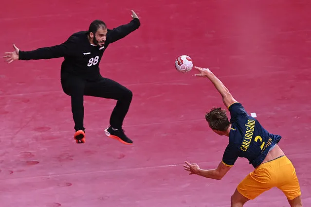 Egypt's goalkeeper Karim Hendawy (L) tries to stop a shot by Sweden's left back Jonathan Carlsbogard during the men's preliminary round group B handball match between Sweden and Egypt of the Tokyo 2020 Olympic Games at the Yoyogi National Stadium in Tokyo on July 30, 2021. (Photo by Daniel Leal-Olivas/AFP Photo)