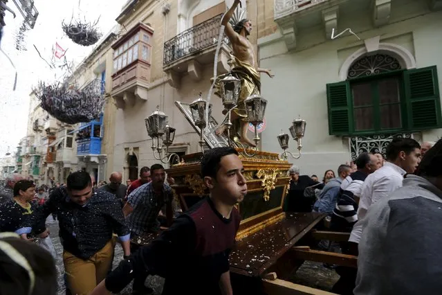 Worshippers run while carrying a statue of the Risen Christ as confetti streams down during an Easter Sunday procession in Cospicua, outside Valletta April 5, 2015. (Photo by Darrin Zammit Lupi/Reuters)