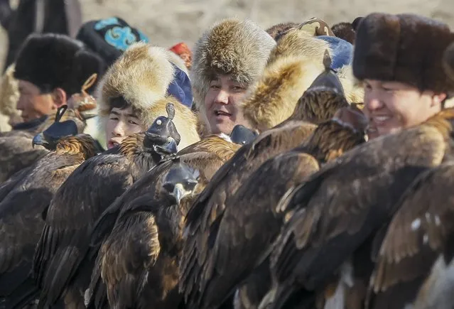 Hunters hold their tamed golden eagles at a parade during the traditional hunting contest outside the village of Nura, east from Almaty, Kazakhstan, February 13, 2016. (Photo by Shamil Zhumatov/Reuters)