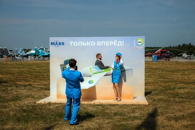 A man and a stewardess pose for a photograph during the opening day of the MAKS-2021 International Aviation and Space Salon at Zhukovsky outside Moscow on July 20, 2021. (Photo by Dimitar Dilkoff/AFP Photo)