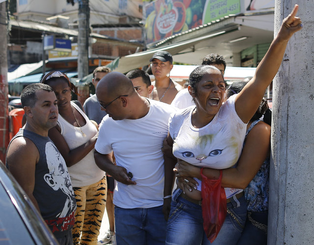 Terezinha Maria de Jesus, right, mother of a 10-year-old boy who was killed by a stray bullet, shouts, “Murderer” at policemen, during a protest in the Alemao slum complex in Rio de Janeiro, Brazil, Saturday, April 4, 2015. Hundreds of people marched through the narrow streets of Rio's largest slum complex in a peaceful demonstration calling an end to the violence that erupts during police operations against suspected drug traffickers. (Photo by Leo Correa/AP Photo)